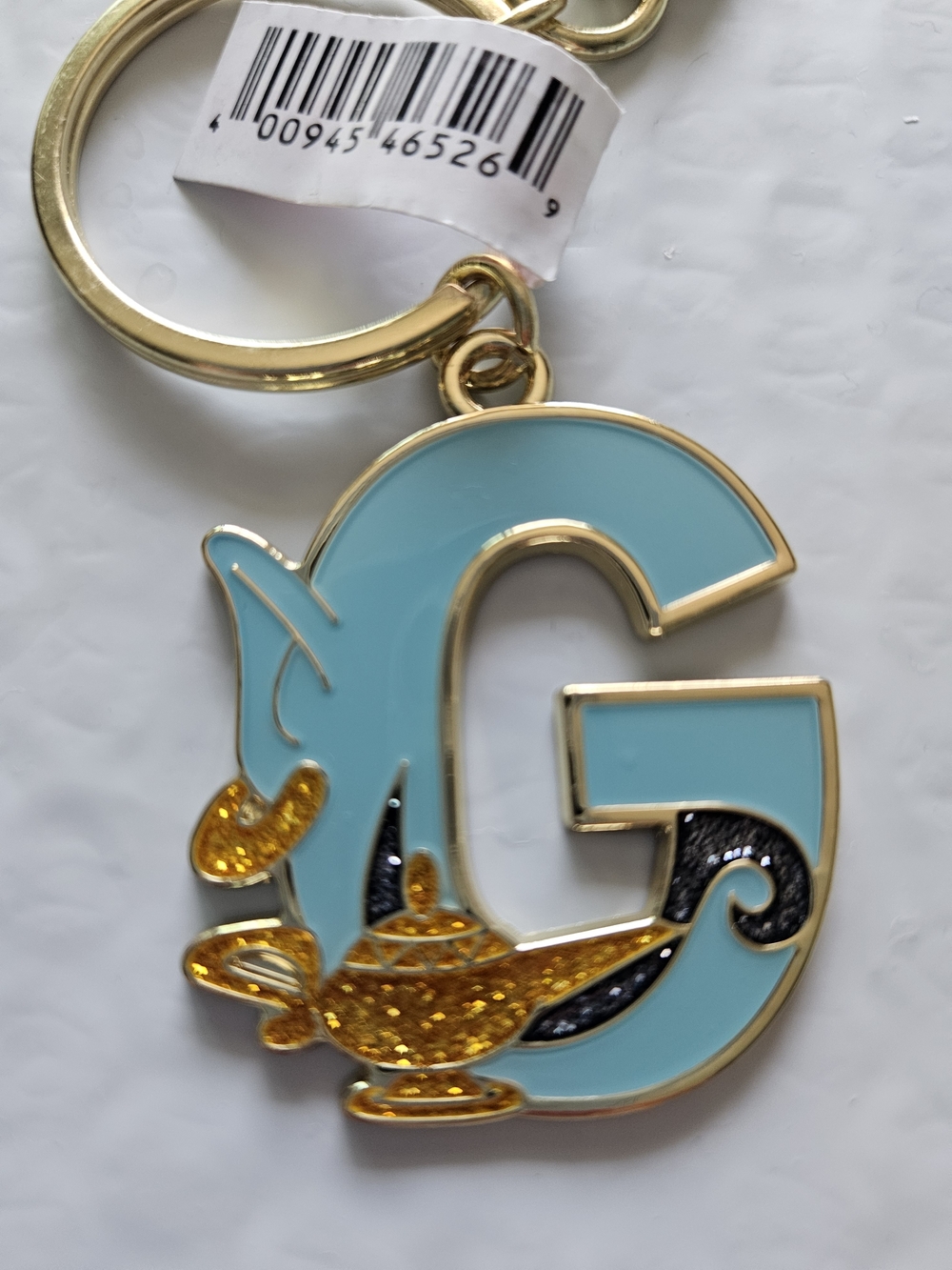 Disney Aladdin Genie G-shaped letter keychain featuring a glittering golden lamp